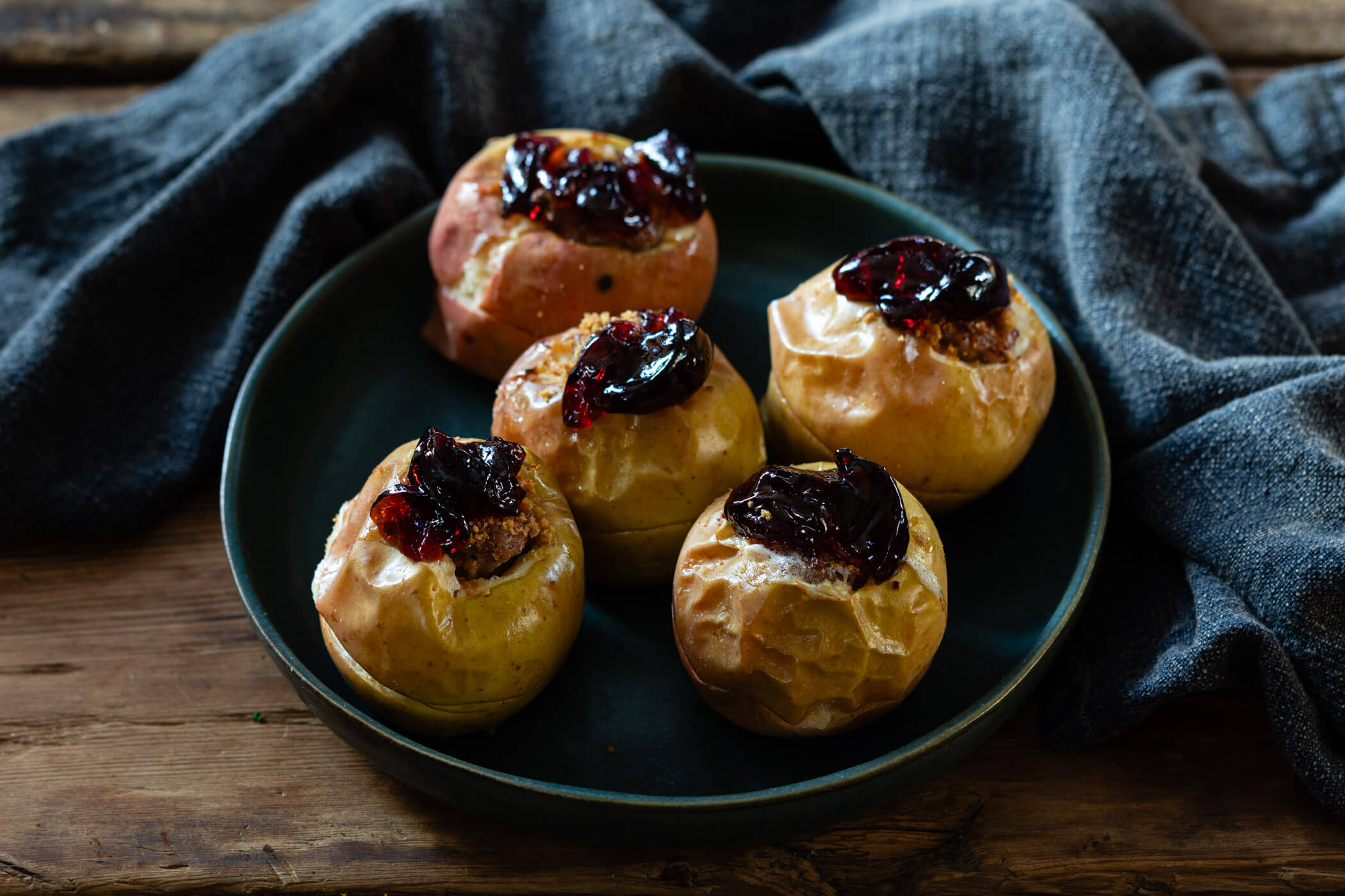 Five roasted Christmas apples filled with sausage and topped with jelly.
