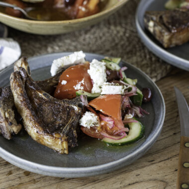 Close-up of hogget chops, plated with Greek salad.