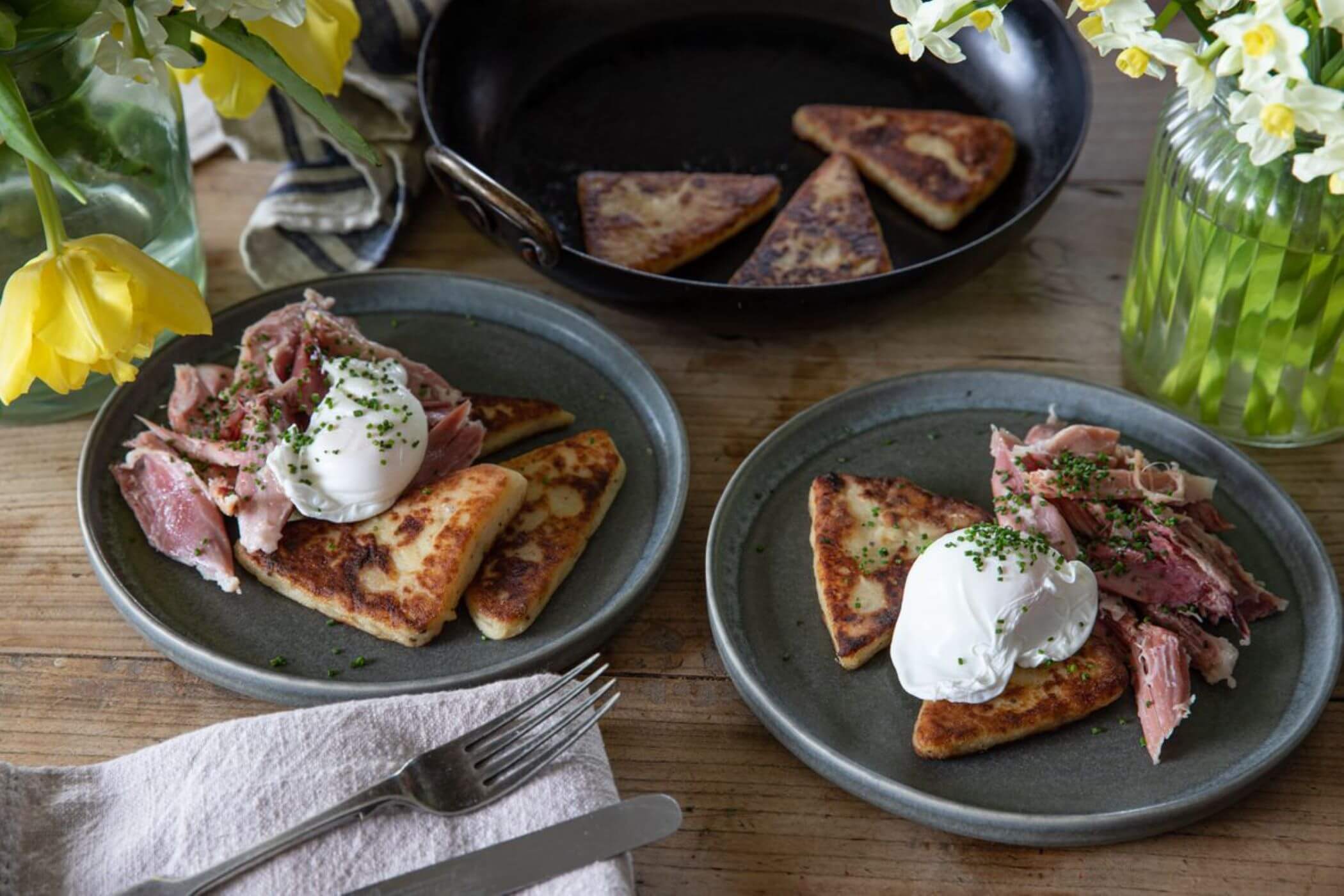 Two plates of potato scones topped with flaked ham hock and a poached egg.
