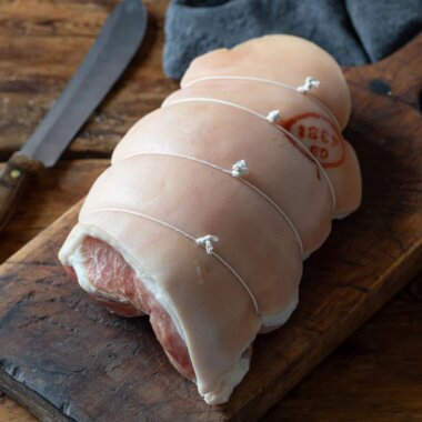 Boneless dry cured York-style ham on a wooden chopping board.