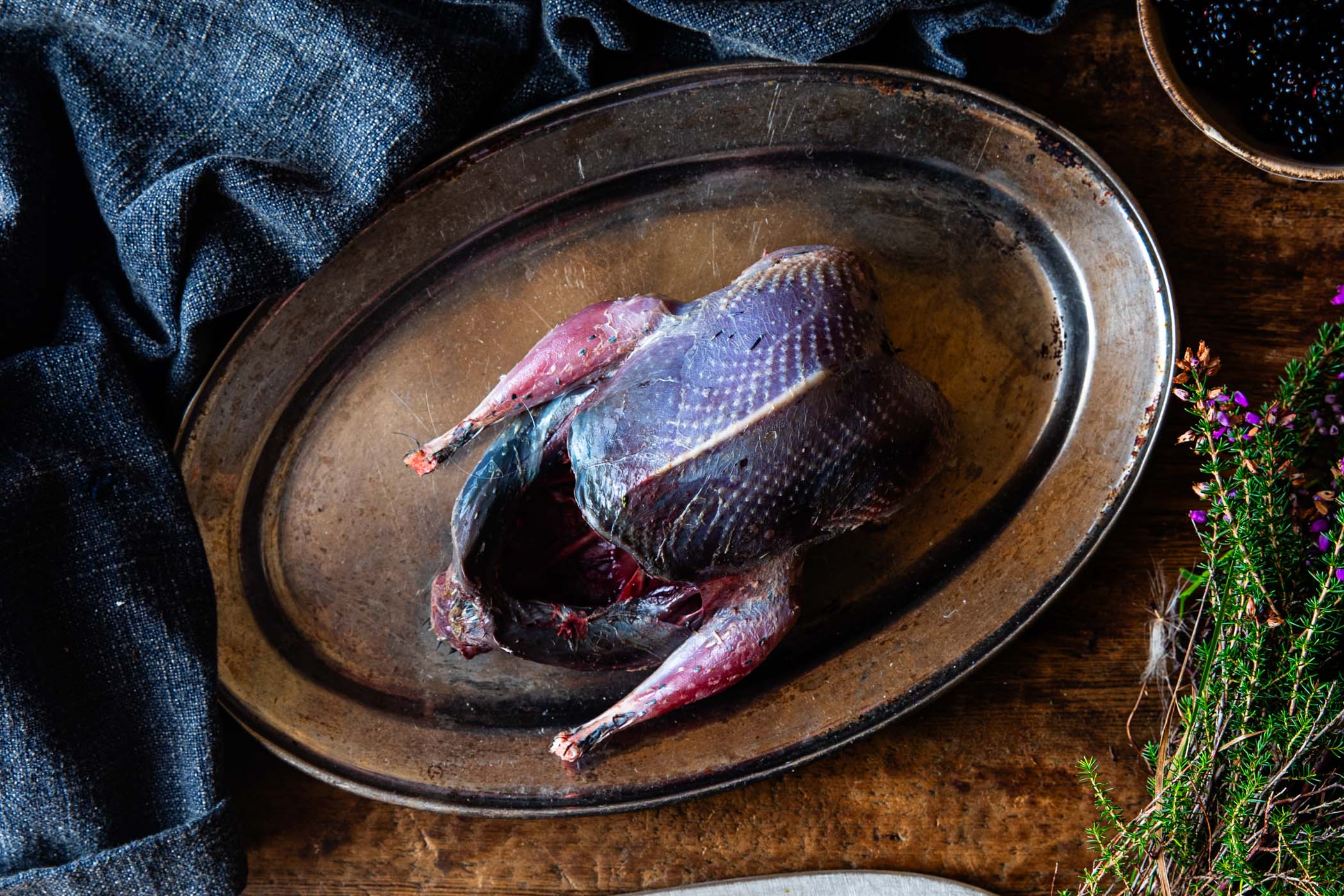 A raw whole grouse on a serving plate.
