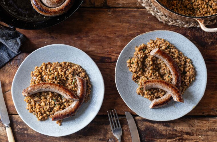 Luganega Sausage on a spelt risotto, served on a pale blue plate. Two portions.