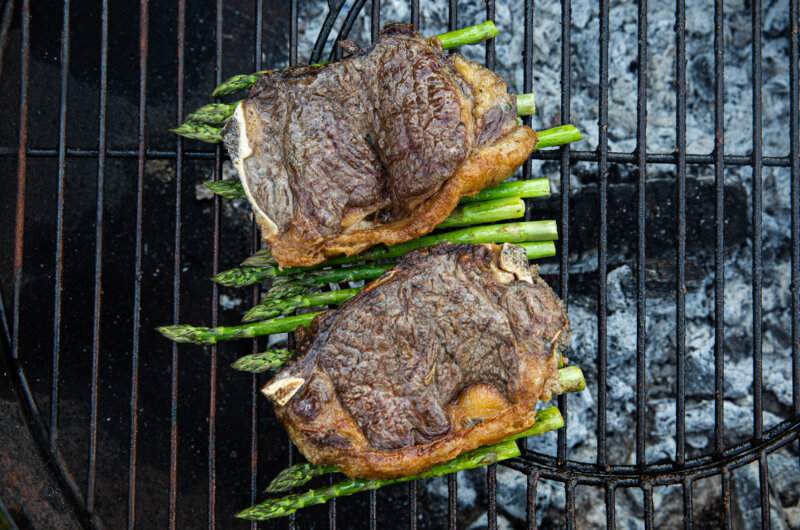 Sirloin steak and asparagus spears on a barbeque grill