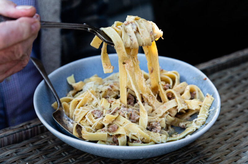 Bowl of fennel sausage ragù served over pasta, topped with grated Parmesan