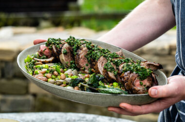 Rolled and stuffed hogget saddle served with borlotti beans, peas, broad beans and a vibrant salsa verde in a large serving dish