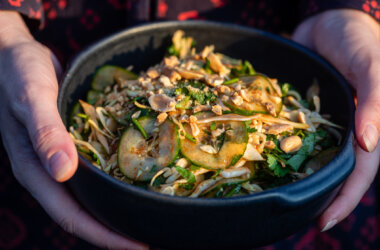 A bowl of fresh cucumber and cabbage salad topped with roasted peanuts and coriander