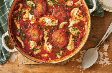 Chicken paprikaš with noklice dumplings cooked in a casserole dish, topped with fresh parsley and served with sour cream