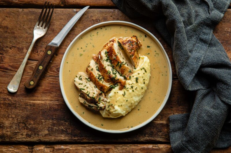 Plated roast chicken breast with Dijon mustard sauce, creamy mashed potato and fresh herbs