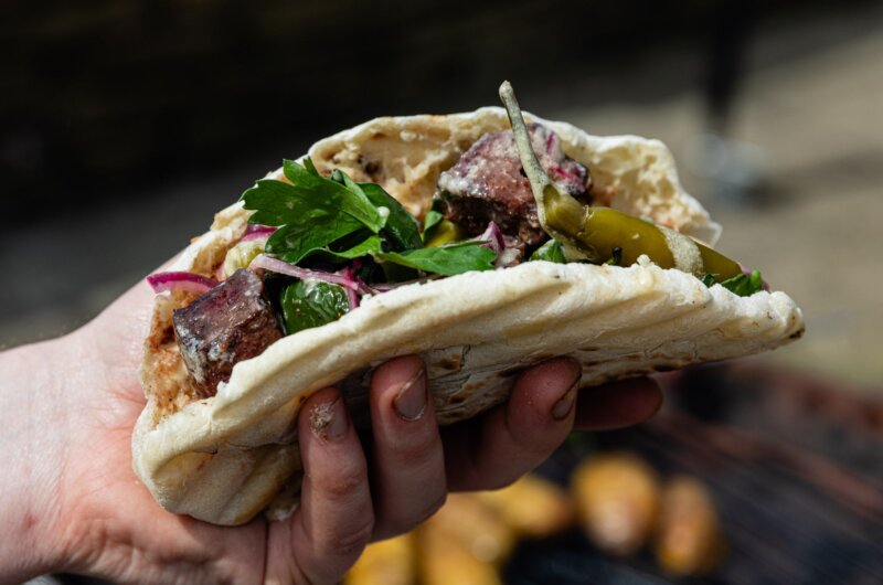 Ox heart pitta being held over a BBQ