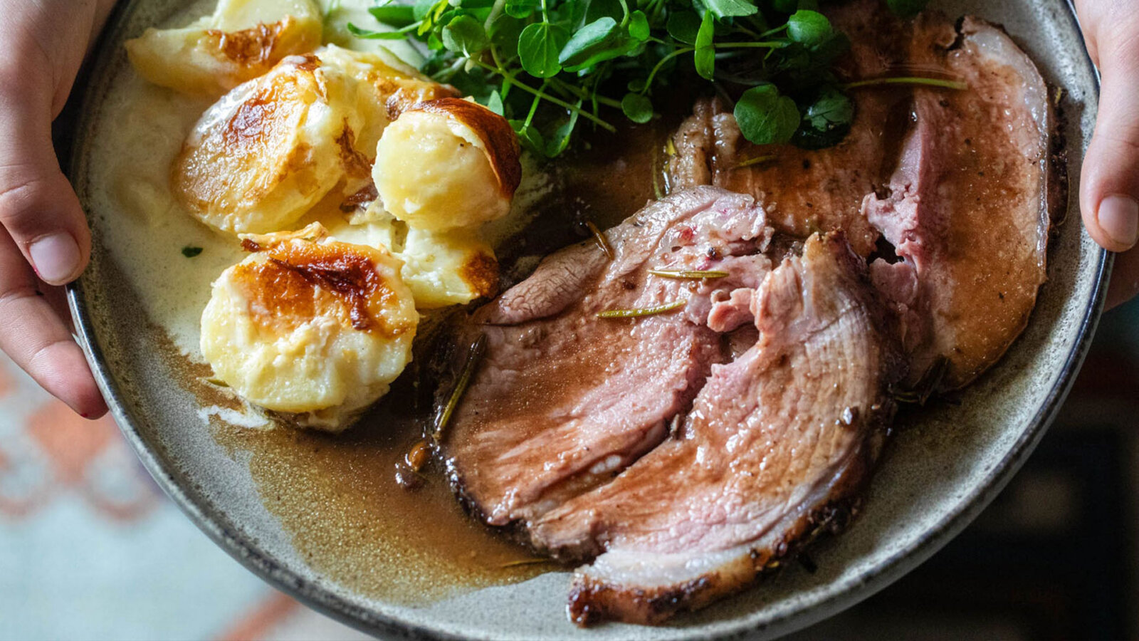 An image of a person holding some plated rolled lamb leg