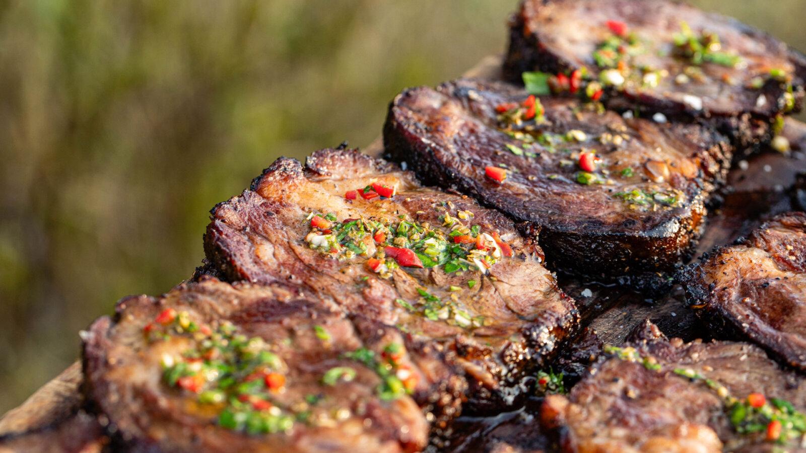 Sliced Swaledale Chuck Eye Roll on a chopping board with chimichurri